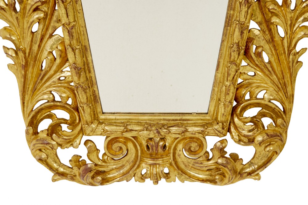 An 18th-century Italian Rococo wall mirror featuring an openwork carved giltwood frame decorated with acanthus leaf scrolls and a decorative cresting around a glass plate. View VII