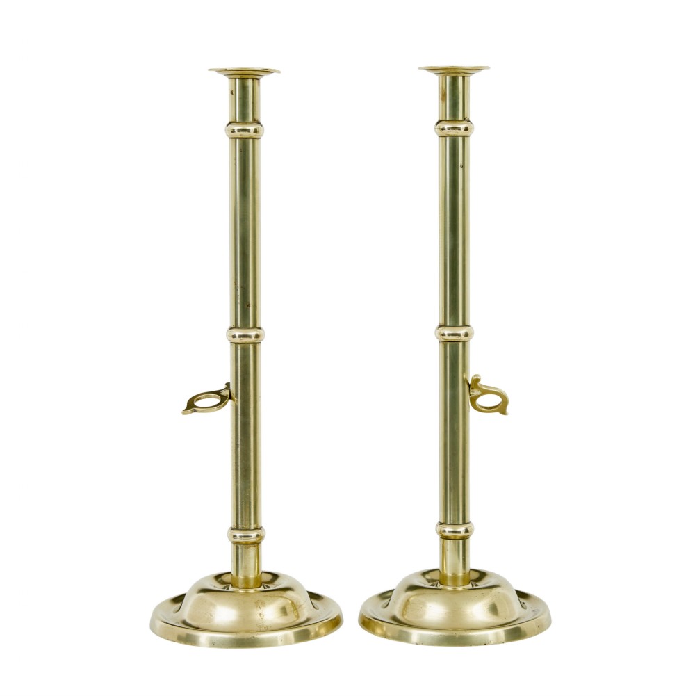 A pair of tall 19th-century Arts and Crafts polished brass candlesticks featuring tubular stems with knops, side loop handles, and domed bases. View II