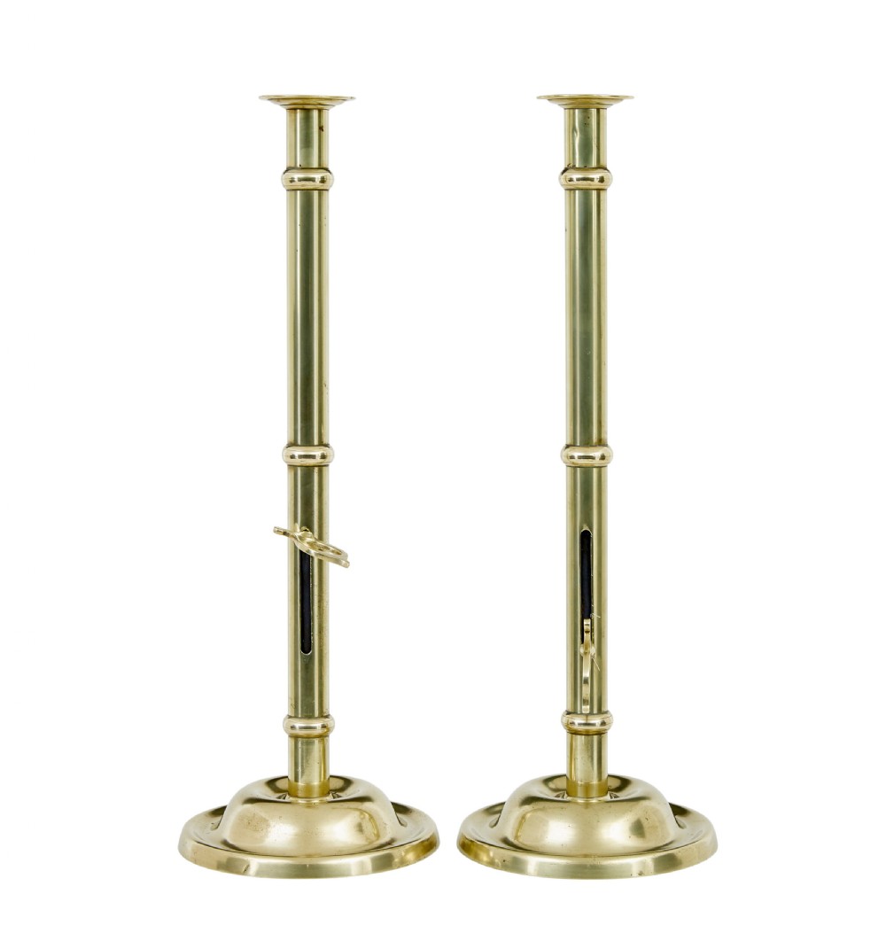 A pair of tall 19th-century Arts and Crafts polished brass candlesticks featuring tubular stems with knops, side loop handles, and domed bases. View III