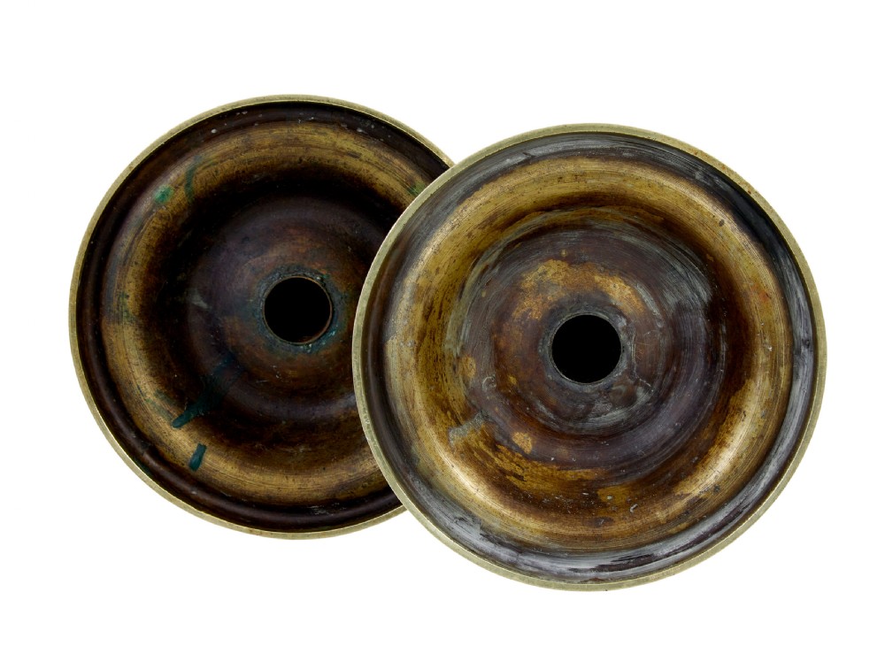 A pair of tall 19th-century Arts and Crafts polished brass candlesticks featuring tubular stems with knops, side loop handles, and domed bases. View V