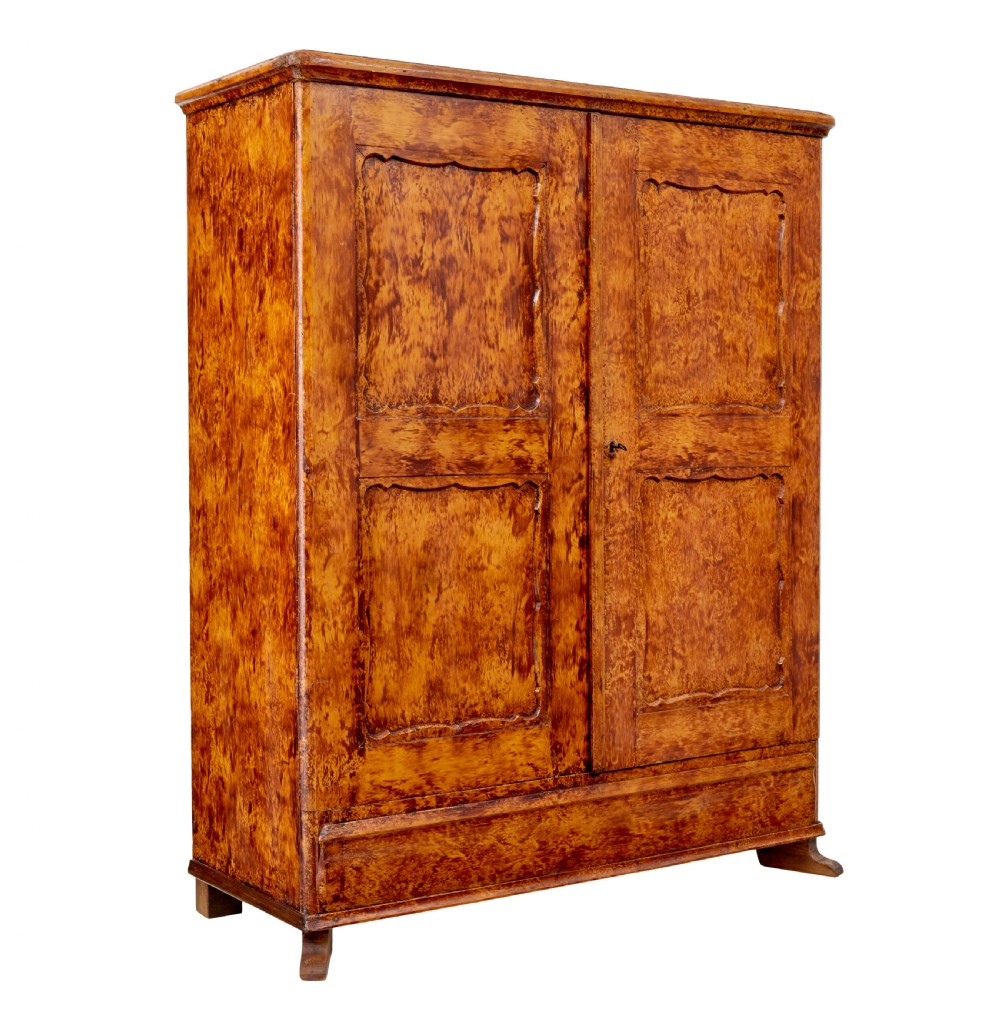 A 19th-century Swedish pine cupboard featuring two panelled doors with a warm amber rag-painted finish and scalloped moulding detailing.