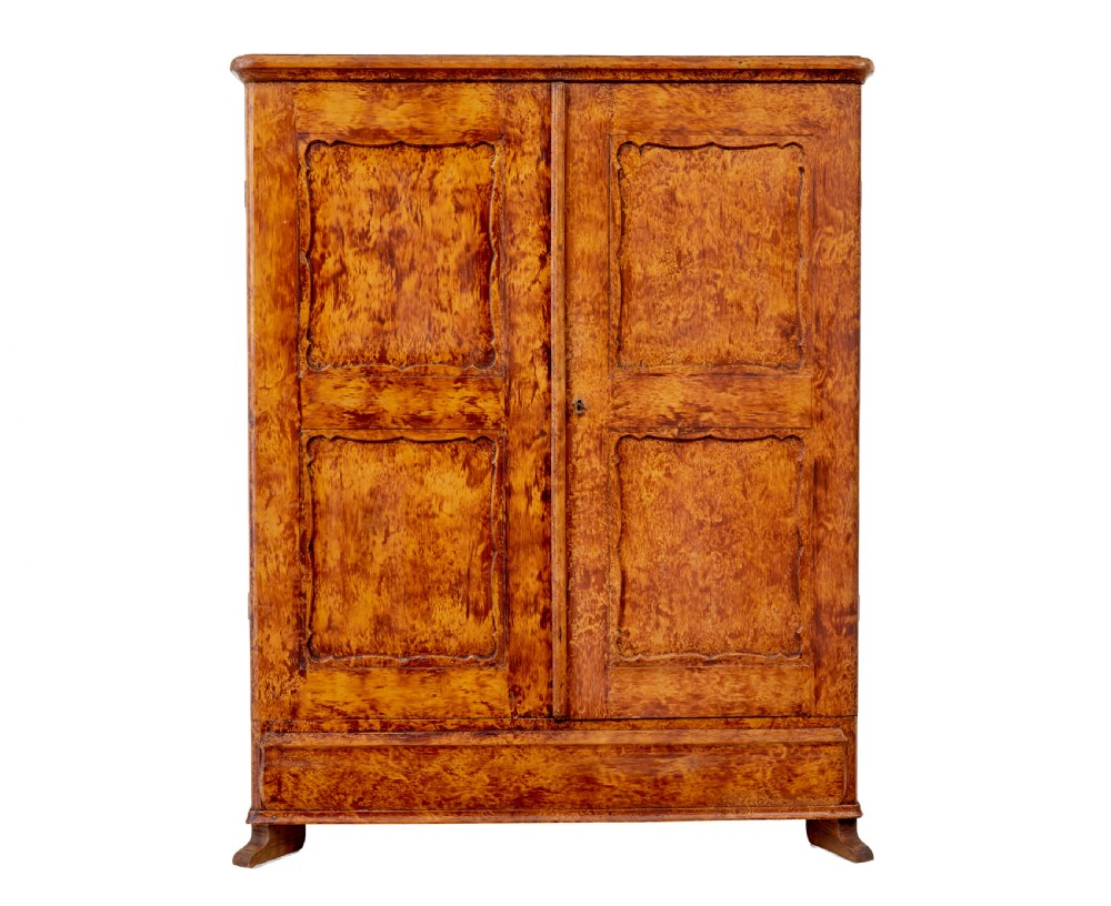 A 19th-century Swedish pine cupboard featuring two panelled doors with a warm amber rag-painted finish and scalloped moulding detailing. View II