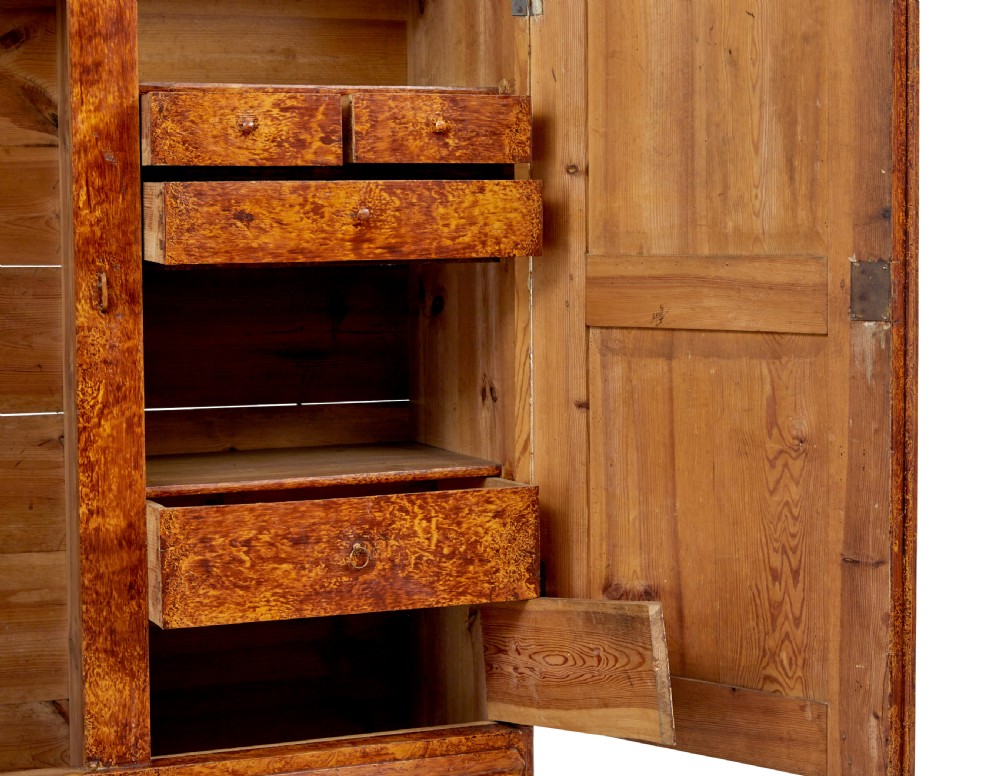 A 19th-century Swedish pine cupboard featuring two panelled doors with a warm amber rag-painted finish and scalloped moulding detailing. View V