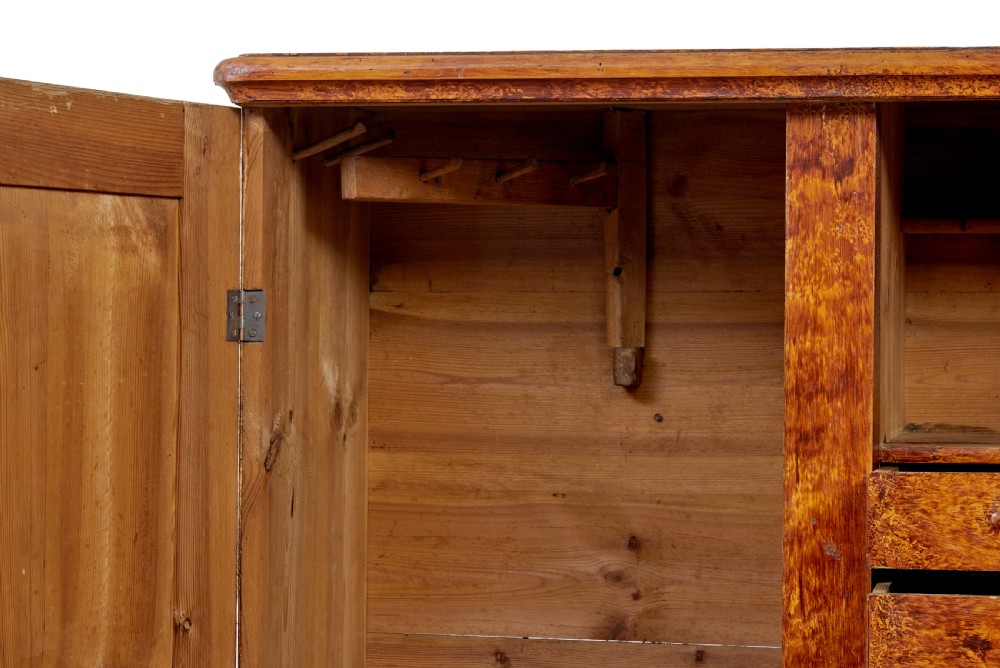 A 19th-century Swedish pine cupboard featuring two panelled doors with a warm amber rag-painted finish and scalloped moulding detailing. View VI