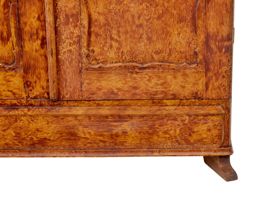 A 19th-century Swedish pine cupboard featuring two panelled doors with a warm amber rag-painted finish and scalloped moulding detailing. View VIII
