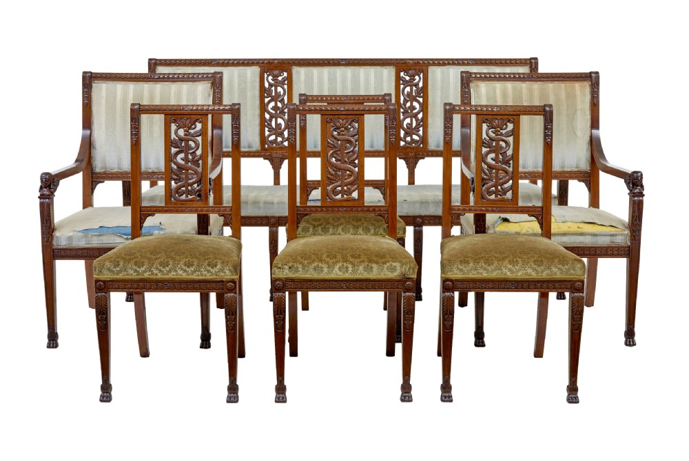 An early twentieth-century seven-piece Empire Revival walnut salon suite comprising a bench, two armchairs, and four side chairs with carved serpent back splats.