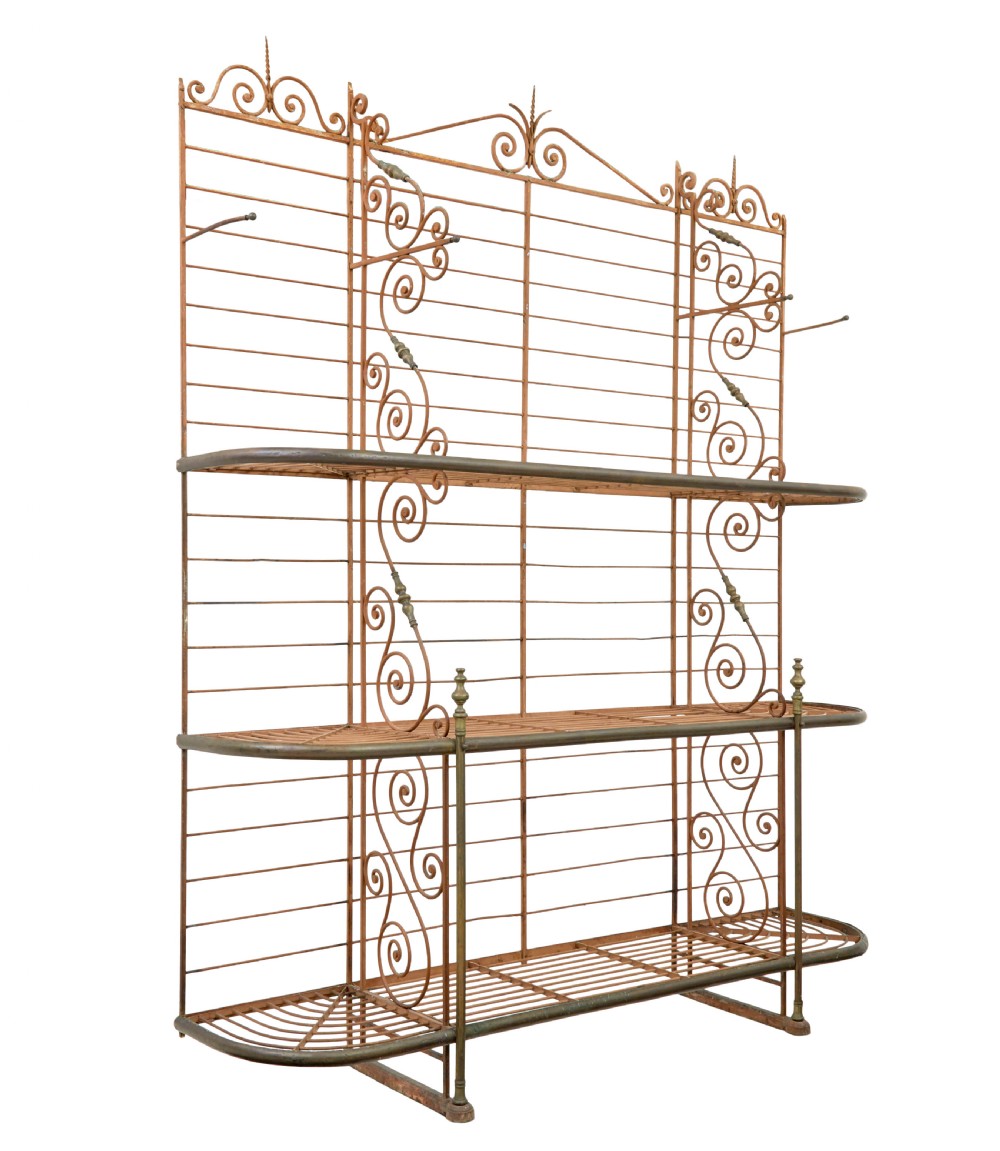 An early 20th-century French wrought iron and brass bakers rack featuring decorative scrollwork and three open slatted shelves.