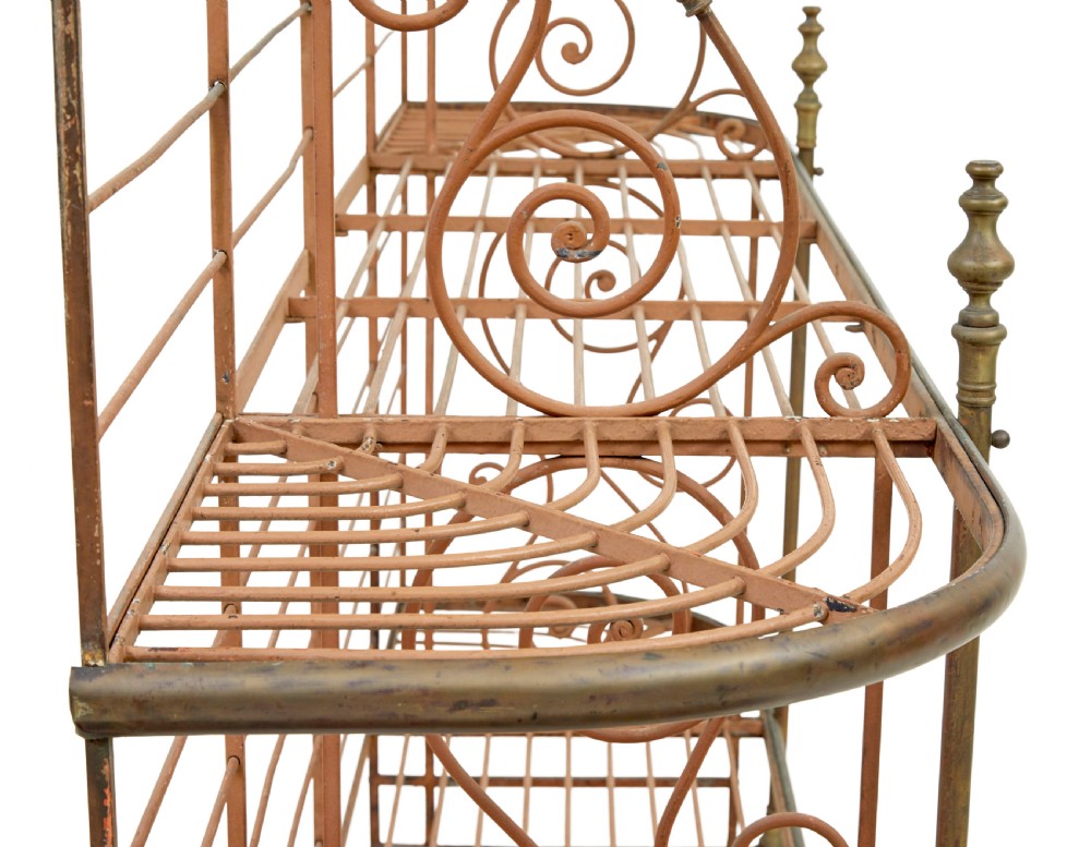 An early 20th-century French wrought iron and brass bakers rack featuring decorative scrollwork and three open slatted shelves. View VI