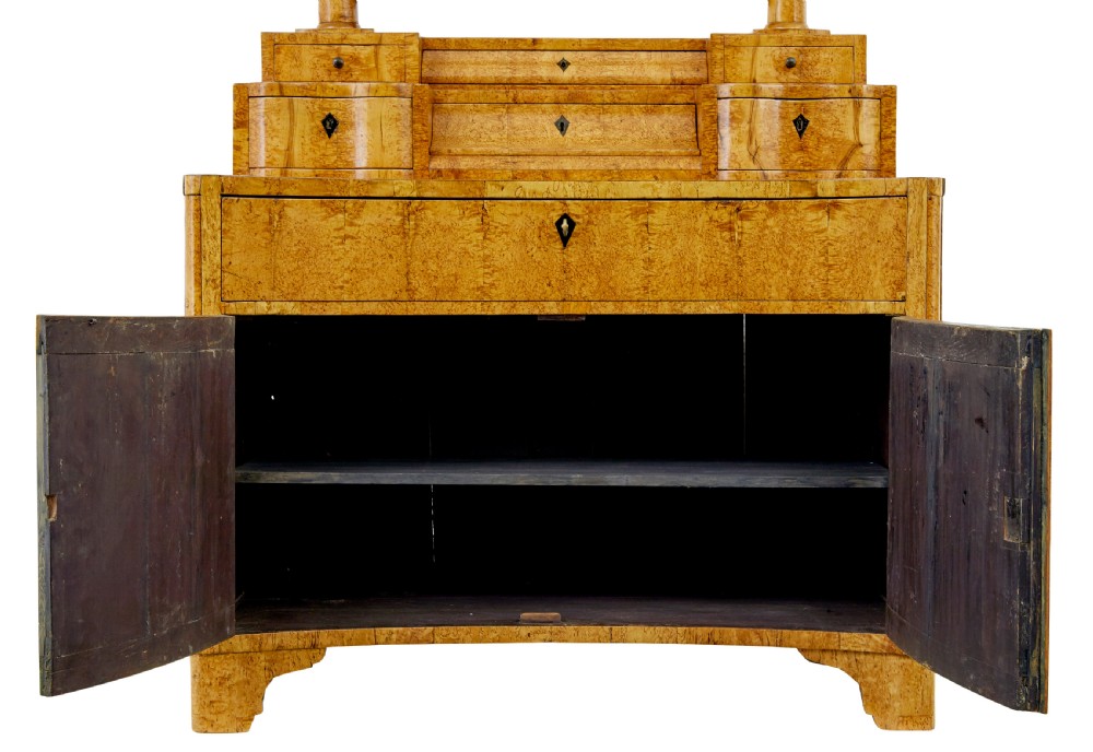 An early 19th-century Biedermeier vanity cabinet featuring a central framed mirror, stepped tier of small drawers, and a double-door base in figured golden birch timber. View VII