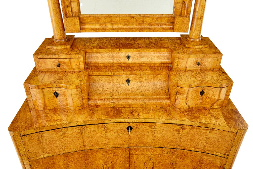 An early 19th-century Biedermeier vanity cabinet featuring a central framed mirror, stepped tier of small drawers, and a double-door base in figured golden birch timber. View VIII