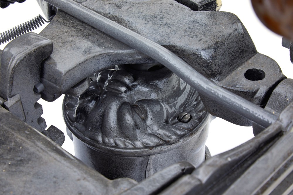 A 19th-century American cast iron dentist chair featuring an adjustable headrest, cream upholstered seat, wooden armrests, and footrest supported by clawed iron feet. View III