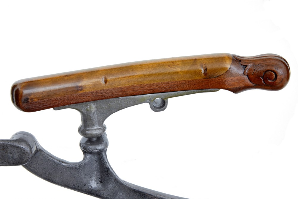 A 19th-century American cast iron dentist chair featuring an adjustable headrest, cream upholstered seat, wooden armrests, and footrest supported by clawed iron feet. View VII