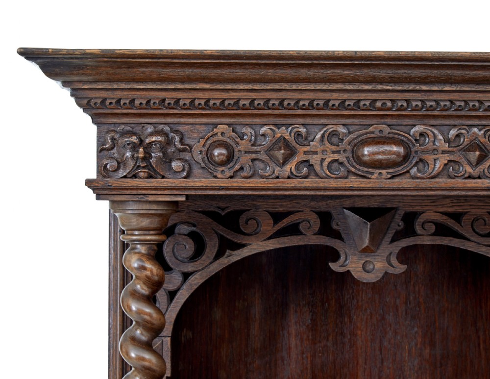 A nineteenth-century Flemish carved oak hall cupboard featuring an upper open niche framed by spiral columns above a single relief-carved door mounted on turned legs. View IX