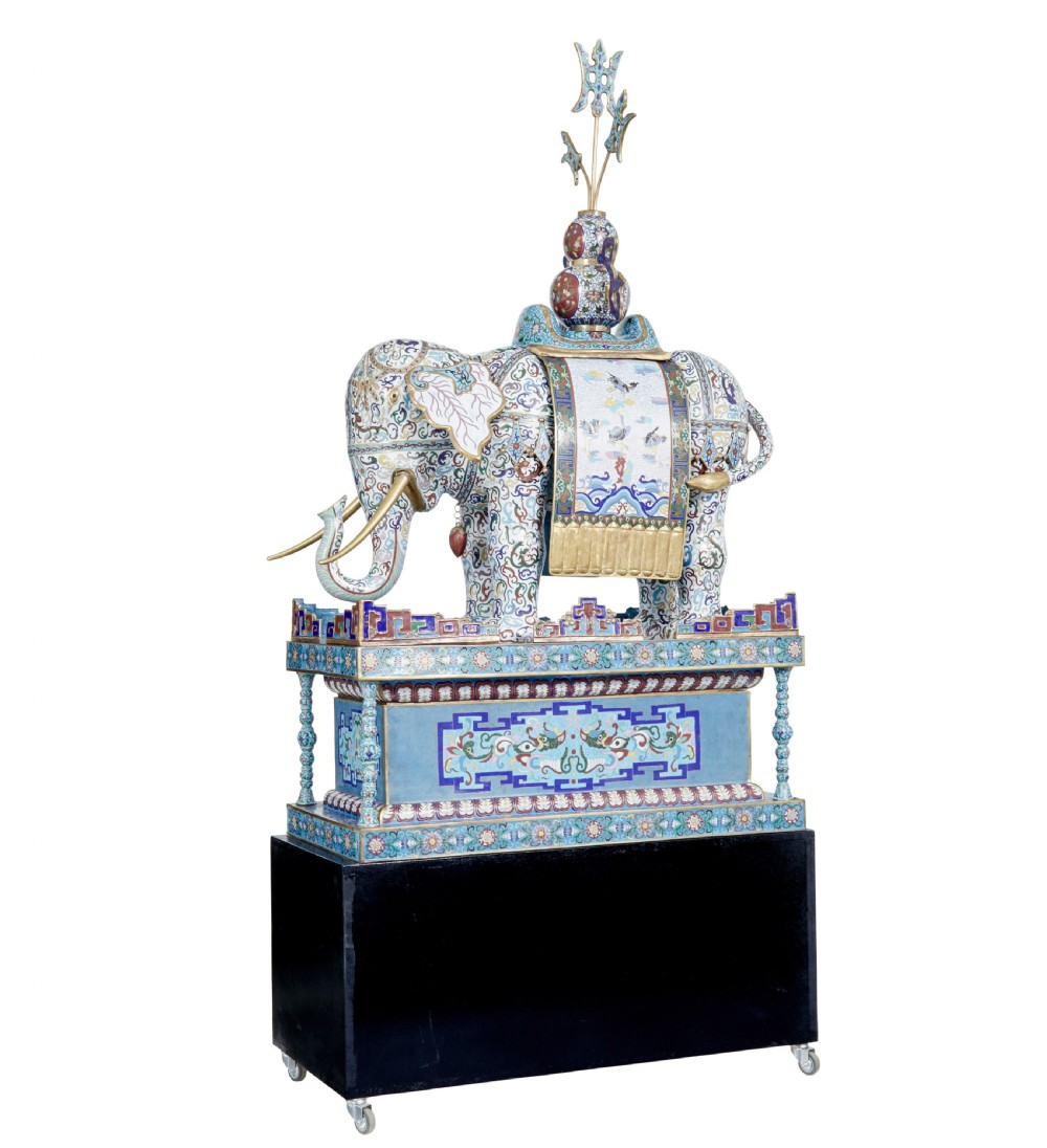 An ornate Chinese cloisonne enamel elephant sculpture with a decorated saddle blanket, standing atop a matching enamel pedestal base.