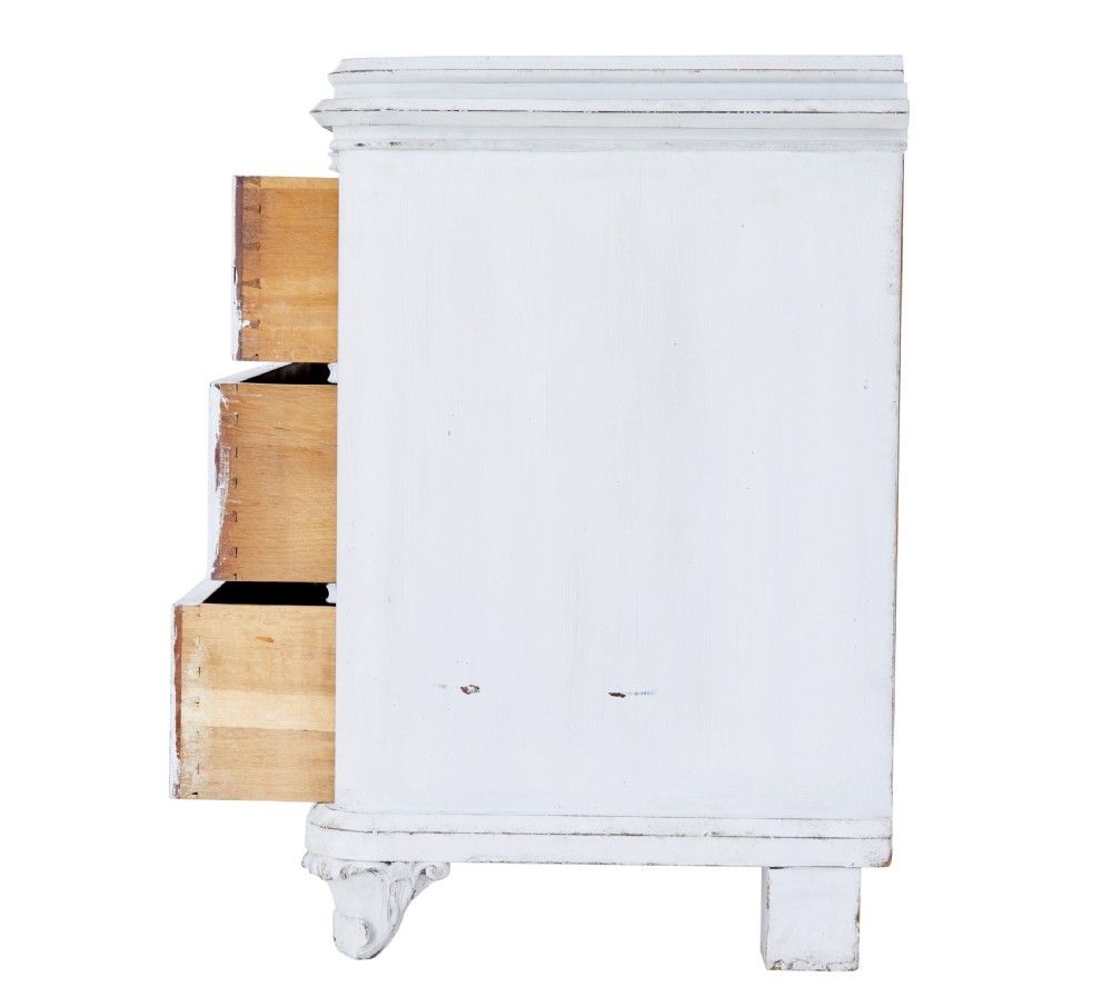 A 19th-century Swedish chest of drawers featuring three long drawers with central escutcheons and a distressed white painted finish resting on carved feet. View V