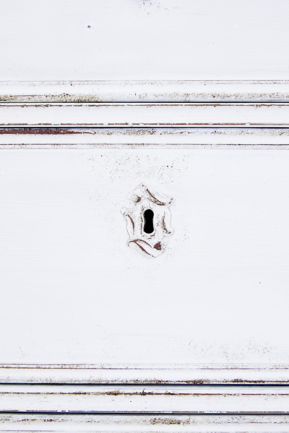 A 19th-century Swedish chest of drawers featuring three long drawers with central escutcheons and a distressed white painted finish resting on carved feet. View IX