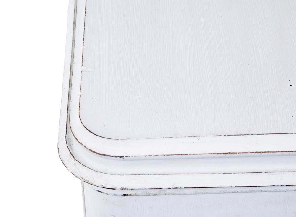 A 19th-century Swedish chest of drawers featuring three long drawers with central escutcheons and a distressed white painted finish resting on carved feet. View XI