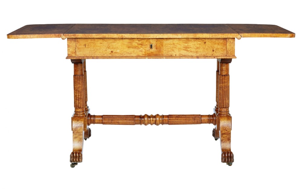 A nineteenth-century Biedermeier burr birch sofa table featuring twin drop leaves, a frieze drawer, fluted column supports, a turned central stretcher, and carved paw feet on castors. View III