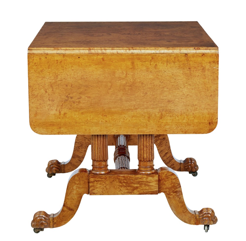A nineteenth-century Biedermeier burr birch sofa table featuring twin drop leaves, a frieze drawer, fluted column supports, a turned central stretcher, and carved paw feet on castors. View V