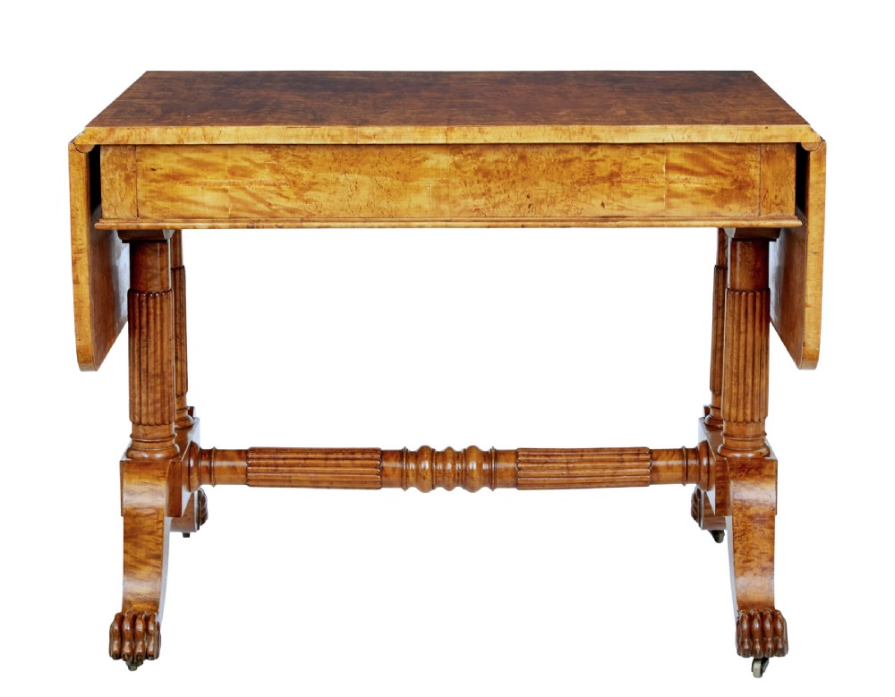 A nineteenth-century Biedermeier burr birch sofa table featuring twin drop leaves, a frieze drawer, fluted column supports, a turned central stretcher, and carved paw feet on castors. View VI