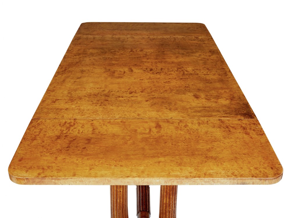 A nineteenth-century Biedermeier burr birch sofa table featuring twin drop leaves, a frieze drawer, fluted column supports, a turned central stretcher, and carved paw feet on castors. View IX