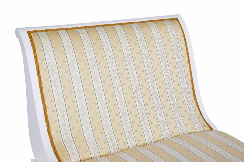 An early 20th-century Scandinavian Empire Revival day bed featuring a white painted frame, flared scroll ends, carved gilded paw feet, and yellow striped fabric upholstery. View IV