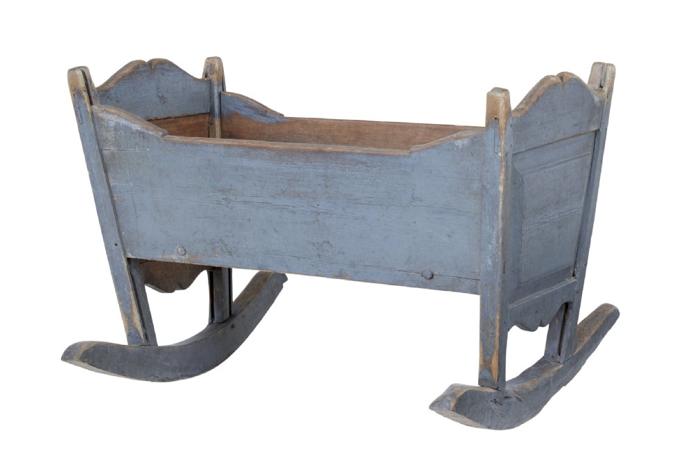A mid 19th century Swedish pine rocking cradle featuring distressed blue paint and carved wooden ends mounted on twin rockers.