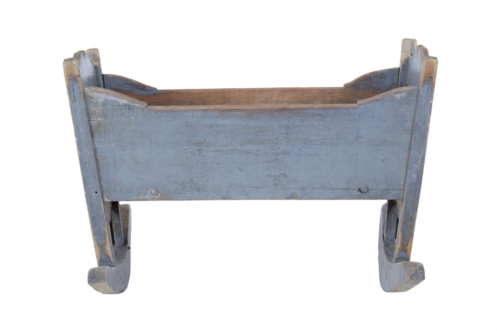 A mid 19th century Swedish pine rocking cradle featuring distressed blue paint and carved wooden ends mounted on twin rockers. View II