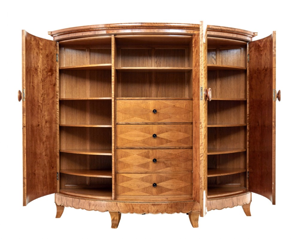 A large curved cabinet crafted from honey-coloured flame birch with four panelled doors, circular beaded keyholes, and a scalloped lower trim. View III