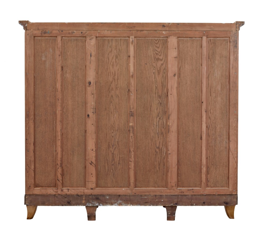 A large curved cabinet crafted from honey-coloured flame birch with four panelled doors, circular beaded keyholes, and a scalloped lower trim. View VI