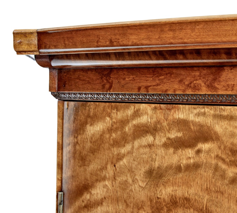A large curved cabinet crafted from honey-coloured flame birch with four panelled doors, circular beaded keyholes, and a scalloped lower trim. View VIII
