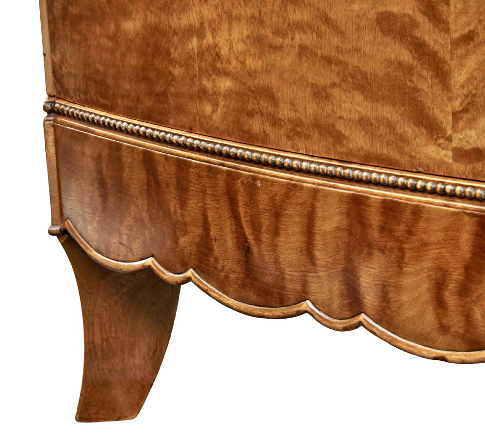 A large curved cabinet crafted from honey-coloured flame birch with four panelled doors, circular beaded keyholes, and a scalloped lower trim. View XIV
