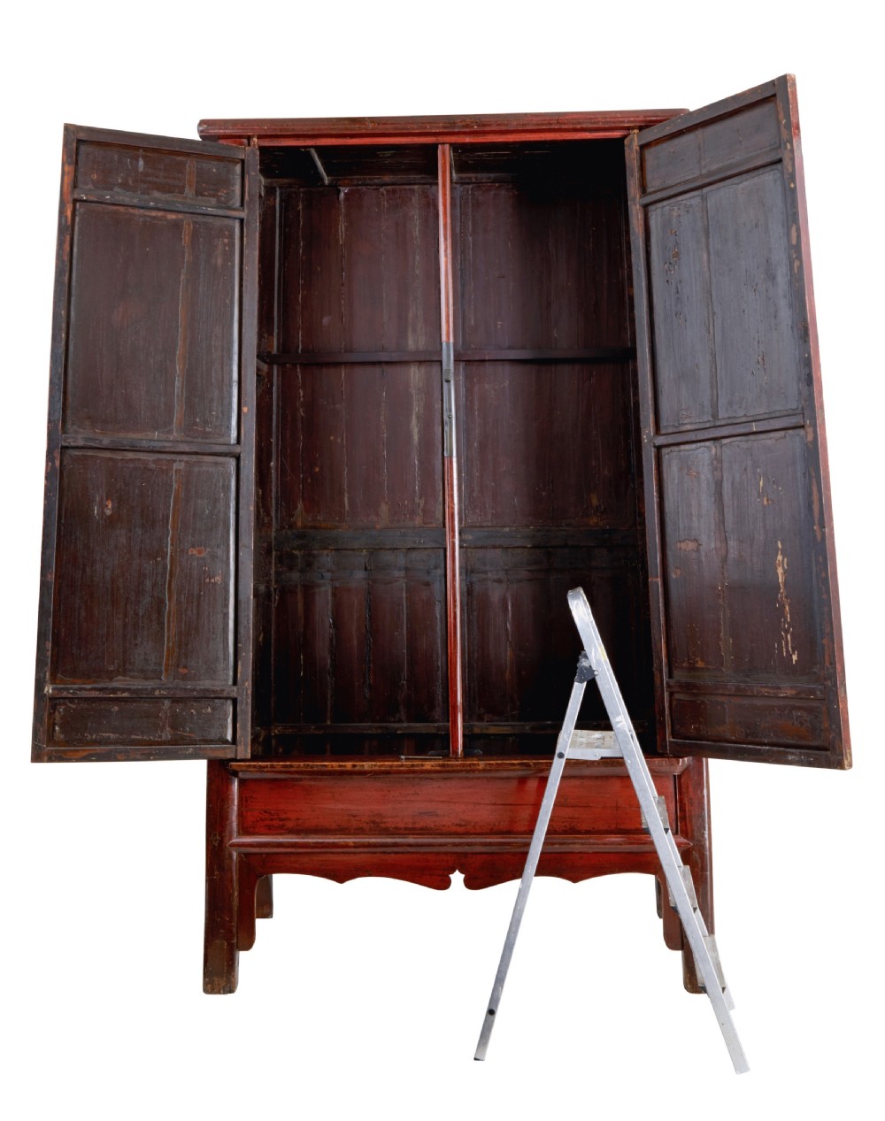 A tall 19th-century Chinese red lacquer cupboard with two panelled doors, metal lockplates, and a shaped lower apron. View II