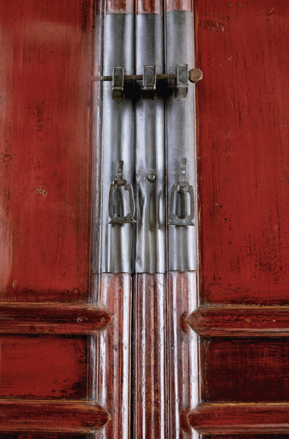 A tall 19th-century Chinese red lacquer cupboard with two panelled doors, metal lockplates, and a shaped lower apron. View VI