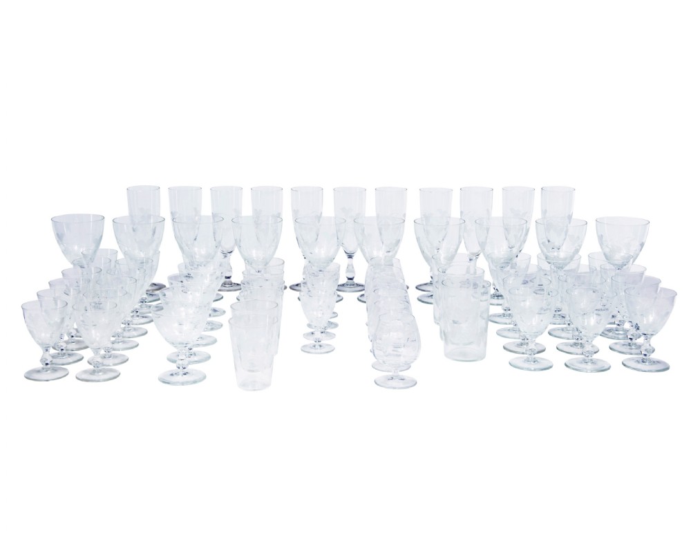 A nine-piece collection of clear 1930s glass stemware and tumblers with etched vine patterns arranged in a line. View II
