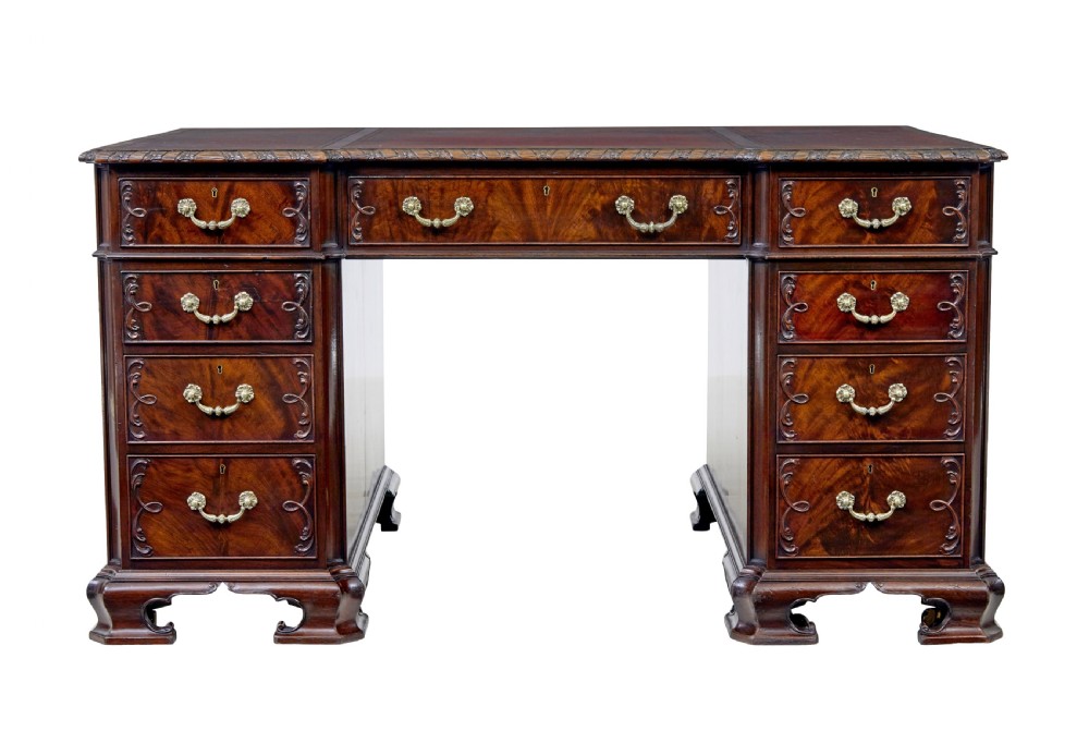 An early 20th-century mahogany pedestal desk featuring nine carved drawers with brass handles, a leather inset top, and bracket feet. View II