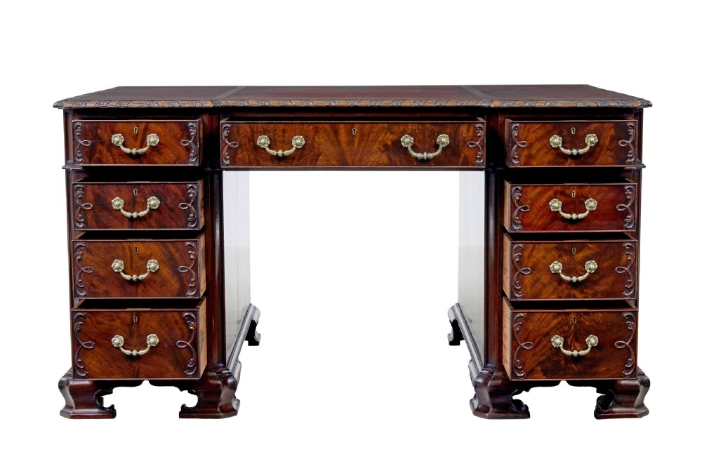 An early 20th-century mahogany pedestal desk featuring nine carved drawers with brass handles, a leather inset top, and bracket feet. View III