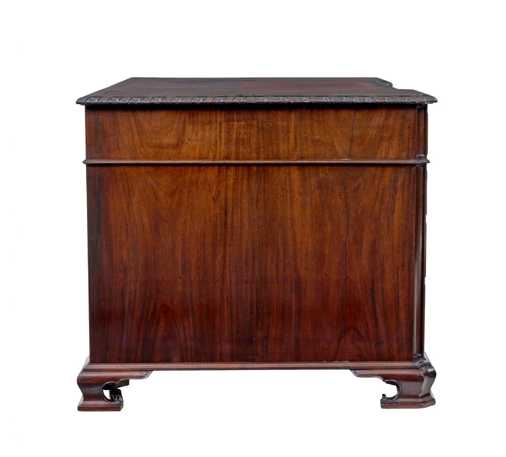An early 20th-century mahogany pedestal desk featuring nine carved drawers with brass handles, a leather inset top, and bracket feet. View VII