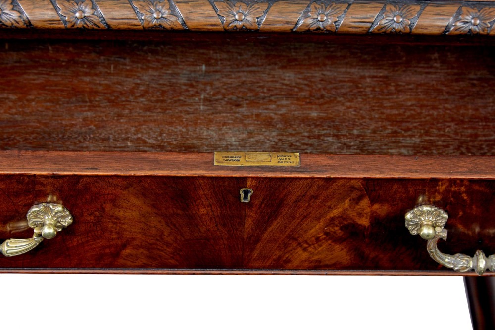 An early 20th-century mahogany pedestal desk featuring nine carved drawers with brass handles, a leather inset top, and bracket feet. View XII