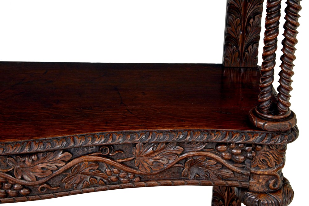 A 19th-century dark oak Victorian buffet featuring three tiers, intricate grapevine relief carvings, turned support columns, and a lower double-door cupboard. View IV