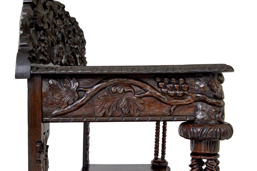 A 19th-century dark oak Victorian buffet featuring three tiers, intricate grapevine relief carvings, turned support columns, and a lower double-door cupboard. View V