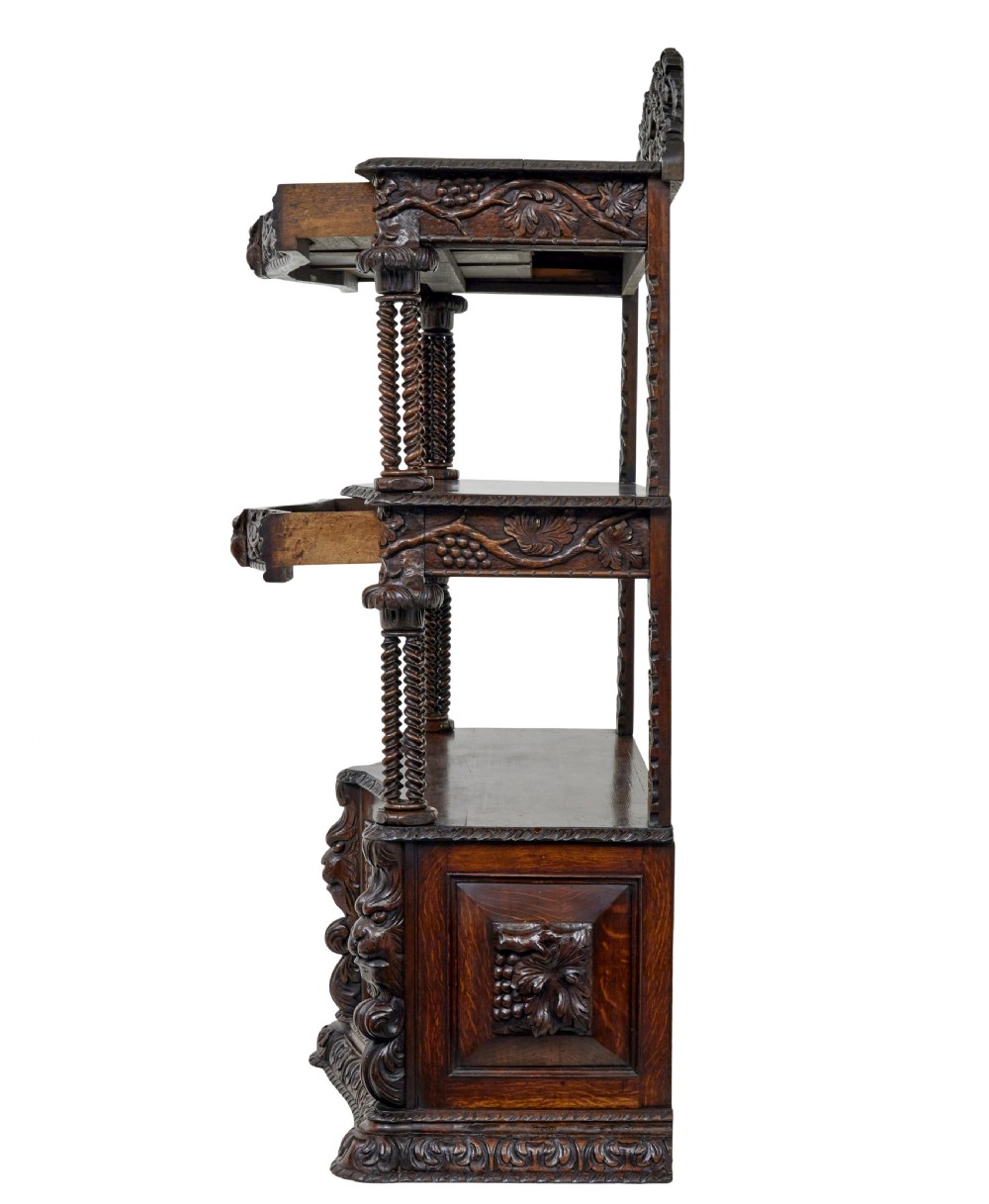 A 19th-century dark oak Victorian buffet featuring three tiers, intricate grapevine relief carvings, turned support columns, and a lower double-door cupboard. View VIII