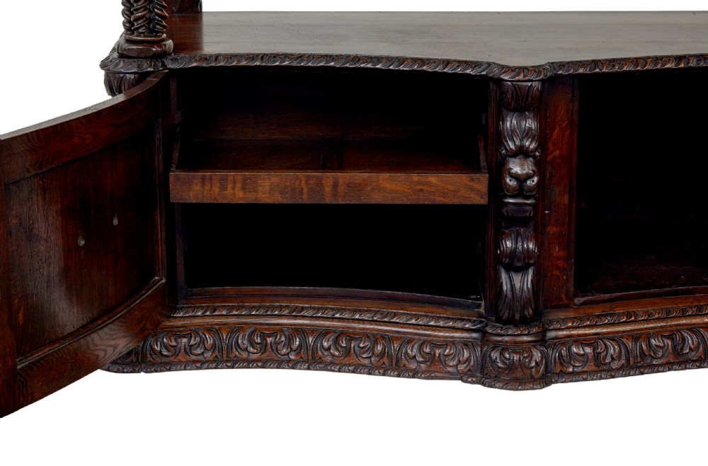 A 19th-century dark oak Victorian buffet featuring three tiers, intricate grapevine relief carvings, turned support columns, and a lower double-door cupboard. View IX