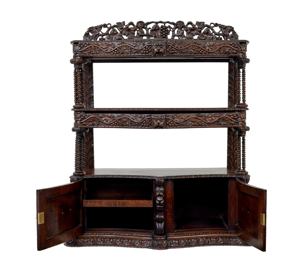 A 19th-century dark oak Victorian buffet featuring three tiers, intricate grapevine relief carvings, turned support columns, and a lower double-door cupboard. View X