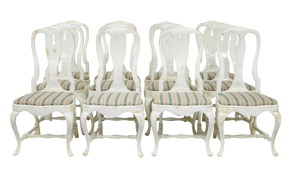A set of fourteen distressed off-white lacquered Queen Anne style dining chairs featuring vasiform splats, cabriole legs, and striped textile upholstery. View II