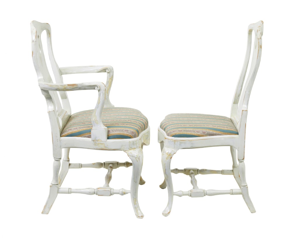 A set of fourteen distressed off-white lacquered Queen Anne style dining chairs featuring vasiform splats, cabriole legs, and striped textile upholstery. View V