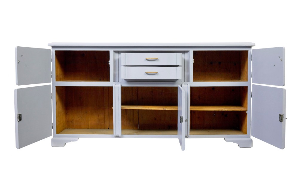 A pale blue-grey painted pine kitchen sideboard featuring five panelled cupboard doors and two central stacked drawers. View III