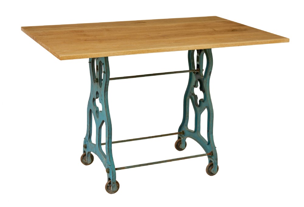 An industrial table featuring a rectangular natural oak top supported by a blue painted cast iron machine base on castors.