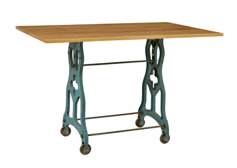 An industrial table featuring a rectangular natural oak top supported by a blue painted cast iron machine base on castors. View II