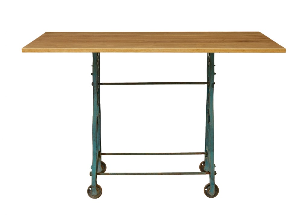 An industrial table featuring a rectangular natural oak top supported by a blue painted cast iron machine base on castors. View III
